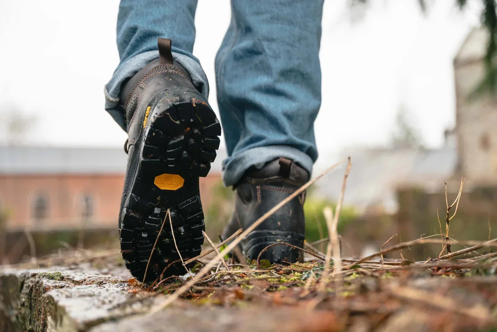 Walker wearing rugged hiking boots on a wet woodland path