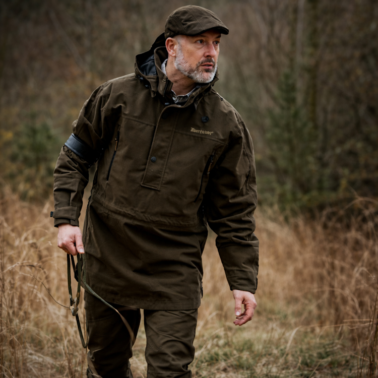 Man in a Deerhunter Pro Gamekeeper Smock walking through a field.